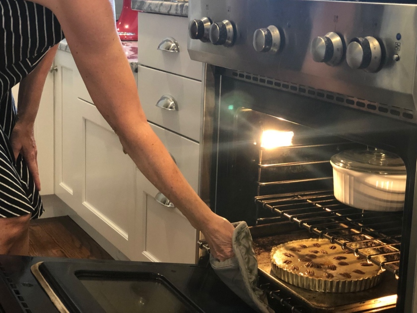  Putting the Sweet Potato Pecan Pie in the oven. Using a cookie sheet prevents spillover messes in the oven. 